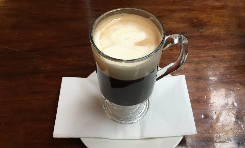 One coffee in a glass mug on white plate